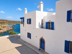 a white building with blue windows and a body of water at Azure Sea House in Avlemonas