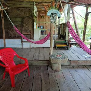 a red chair and hammock on a wooden deck at TANGARA Hostel in Buenaventura
