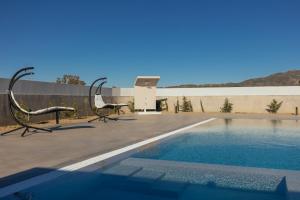 a swimming pool with two chairs next to a building at Villa Samantha - Private Pool, 3 Ensuite Bedrooms & Complete Privacy near Laganas, By TK Premium Stays in Ambelókipoi +40 photos