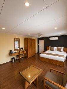 a bedroom with a bed and a desk and a table at Hotel Meridien Riverfront in Srinagar +21 photos