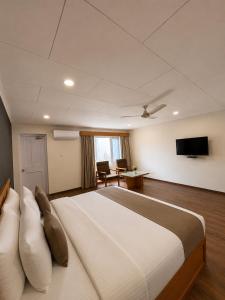 a bedroom with a large bed and a desk at Hotel Meridien Riverfront in Srinagar