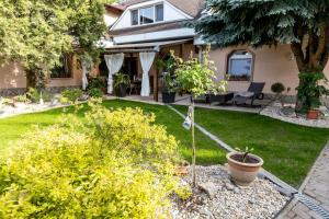 a house with a yard with bushes and trees at Apartman Karlina 100 m2 Terrace Garden in Šahy