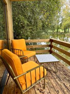 two chairs and a table on a porch at Les Rives De Bel Air - Hébergements - Camping - Caravaning in Saint-Siméon +14 photos