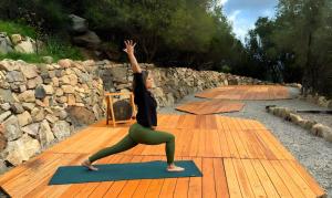 a woman doing a yoga pose on a yoga mat at Bioloco - sea, nature, pool in Castiadas
