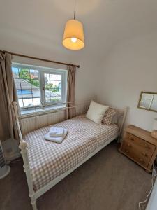 a small bedroom with a bed with a window at Holly Cottage in Edwinstowe