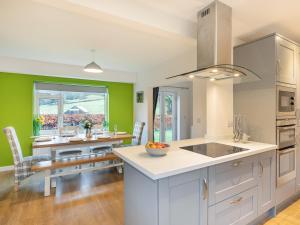 a kitchen with green walls and white cabinets and a table at Carr View Farm in Bamford