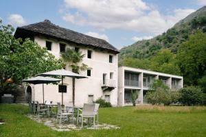 a building with chairs and umbrellas in front of it at Casa Martinelli, Boutique-Hotel in Maggia
