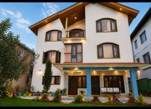 a large white house with a balcony at Minnat Home Stay in Srinagar