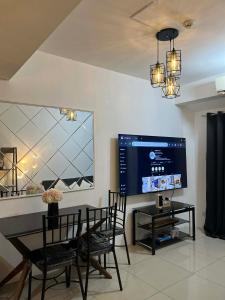 a dining room with a table and a large screen tv at Shell Staycation in Manila