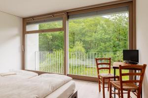 a bedroom with a bed and a desk and a large window at Casa Martinelli, Boutique-Hotel in Maggia