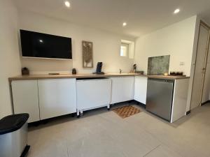 a kitchen with white cabinets and a flat screen tv at logement centre Bourg, parking privé in Bourg-en-Bresse +2 photos