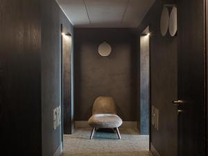 a chair in a hallway with a black wall at ME by Meliá Milan Il Duca in Milan