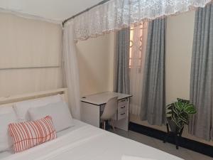 a bedroom with a bed and a desk and a window at Shalom - Stays in Voi