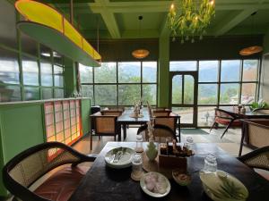 a dining room with tables and chairs and windows at Tora House in Nagar +59 photos