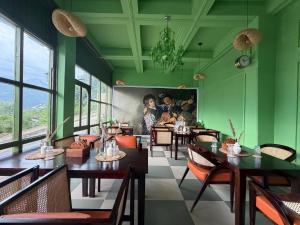 a restaurant with green walls and wooden tables and chairs at Tora House in Nagar