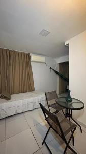 a room with a table and a bed with a window at Fenomenall Kitnet in Campina Grande