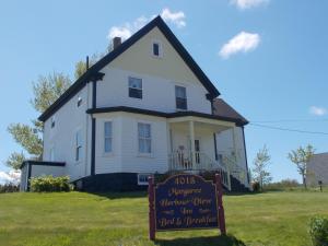 a white house with a sign in front of it at Margaree Harbour View Inn B&B in Margaree Harbour