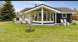 a house with a tree in the yard at Cozy And Well-Maintained Holiday Home in Eskebjerg +1 photo