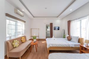 a bedroom with a bed and a couch and windows at Chic Studio Homestay in Hue