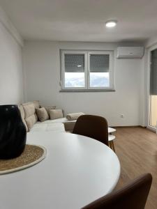 a white living room with a couch and a table at Apartman M&M in Teslić