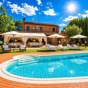 a swimming pool in front of a house with umbrellas at Villa Ferrara, resort e Location per eventi in Coriano