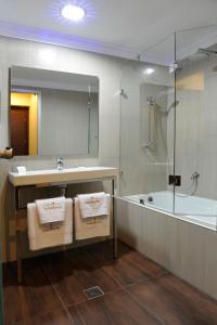 a bathroom with a sink and a tub and a mirror at Europa Hotel in Kastoria +24 photos