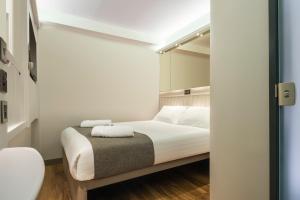 a bedroom with a bed with white sheets and pillows at Point A Hotel London Shoreditch in London