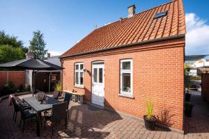 a small brick house with a table and an umbrella at Cozy Central Located Townhouse In Nakskov in Nakskov