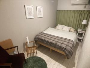 a small bedroom with a bed and a green curtain at Firmament Shimoshinjo in Osaka