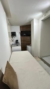 a large bed in a room with a kitchen at Fenomenall Kitnet in Campina Grande