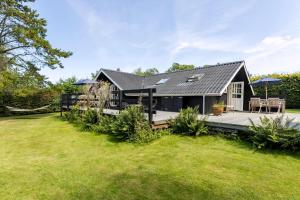 a black house with a deck and a yard at Idyllic Summer House Close To Beach And Forest in Tisvildeleje