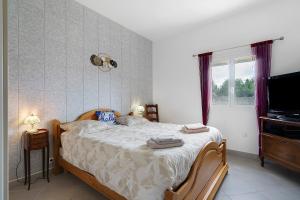 a bedroom with a bed and a tv and a window at Le Cocon Taillonais avec piscine in Saint-Ciers-du-Taillon +27 photos