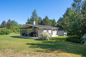 a small white house with a porch in a yard at Well-Designed House In Scenic Surroundings in Martofte