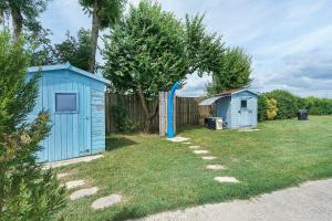 two blue sheds in a yard next to a fence at Le Cocon Taillonais avec piscine in Saint-Ciers-du-Taillon