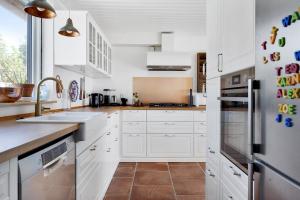 a white kitchen with a sink and a refrigerator at Summerhouse With Both Island Charm And Sea View in Holbæk