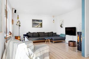 a living room with a couch and a tv at Summerhouse With Both Island Charm And Sea View in Holbæk