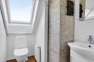 a bathroom with a toilet and a sink and a window at Summerhouse With Both Island Charm And Sea View in Holbæk +17 photos