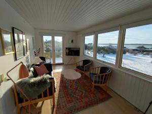 a living room with a couch and chairs and windows at Cozy Summerhouse With Spectacular Views in Ølsted