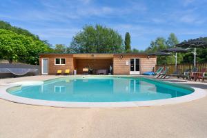 a large swimming pool with a house in the background at La Mailleraie - L'etang in Valojoulx