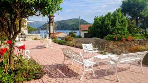 a group of white chairs sitting on a brick patio at ELENA APARTMENTS ITHACa in Vathi