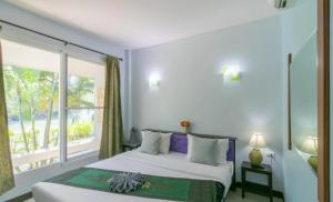 a bedroom with a bed and a large window at Chaiyo Riverfront Resort Phuket in Phuket