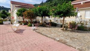 a brick walkway with benches and chairs and trees at ELENA APARTMENTS ITHACa in Vathi