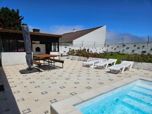 a patio with a pool and a table and chairs at Casa da Uva-Mosteiros Vineyards House-Heated swimming-pool in Mosteiros