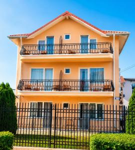 a yellow building with balconies and a fence at Vila Flavia in Costinesti