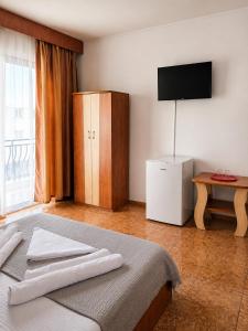 a bedroom with a bed and a cabinet and a television at Vila Flavia in Costinesti