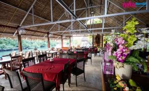 a restaurant with tables and chairs with red table cloth at Chaiyo Riverfront Resort Phuket in Phuket