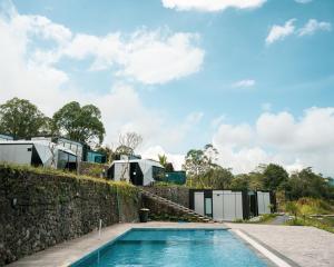 a swimming pool in front of a stone wall with a house at montevela glamping kintamani in Kubupenlokan