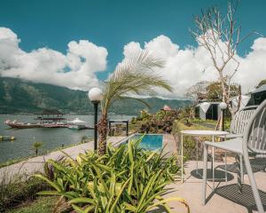 a patio with chairs and a view of the water at montevela glamping kintamani in Kubupenlokan