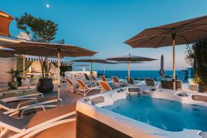 a hot tub on a patio with chairs and umbrellas at Padam Hotel & SPA in Ulcinj