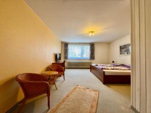 a bedroom with a bed and chairs and a window at Midway Weser Hotel Nienburg in Nienburg